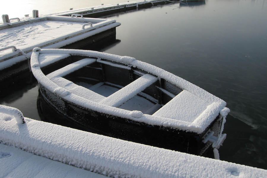 Båt dekket i snø som ligger ved en brygge