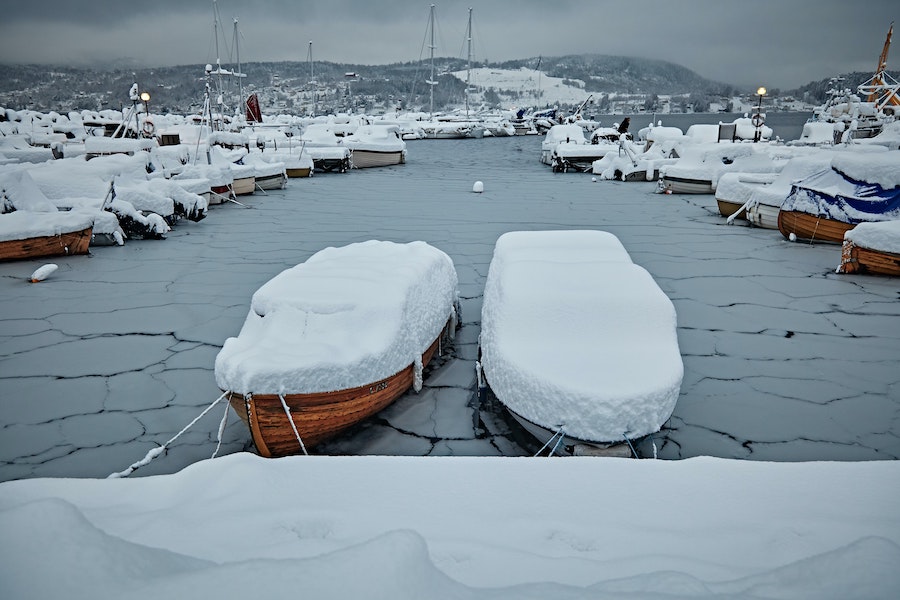 Båter med snø på seg på islagt vann